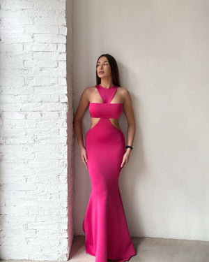 woman in pink cutout gown standing by white brick wall