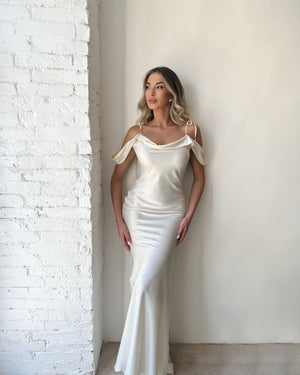 woman in elegant white satin dress standing against white wall