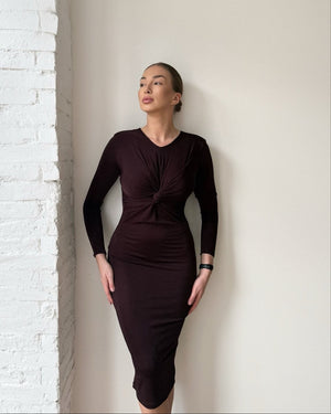 woman wearing dark long sleeve dress standing near white wall