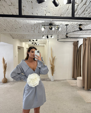 woman in light blue dress with white flower detail in modern room