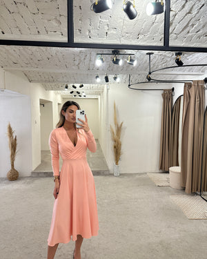 woman wearing peach long sleeve midi dress in modern boutique