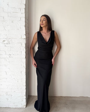 sleek black evening gown model standing white brick wall