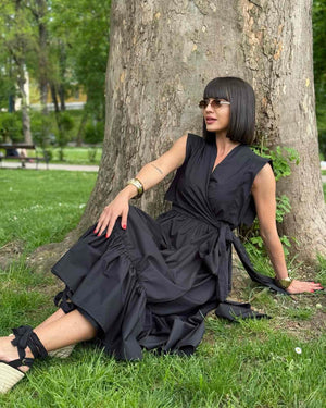 woman in black dress sitting against tree