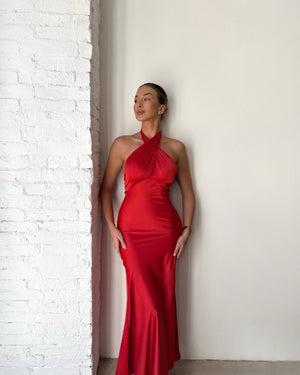woman wearing red halter dress standing against white brick wall