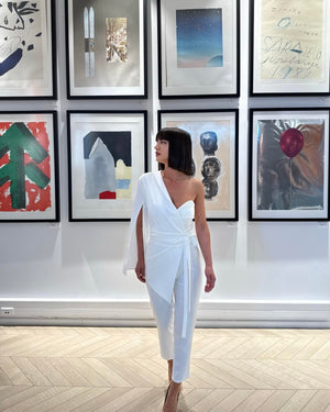 woman in elegant white one sleeve dress in art gallery