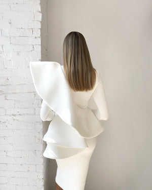white ruffled dress back view against white brick wall