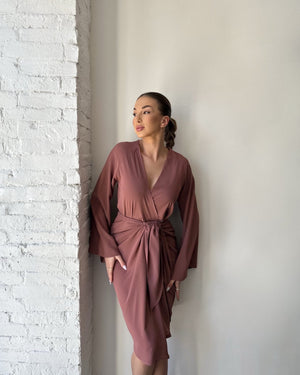 elegant mauve wrap dress against brick wall