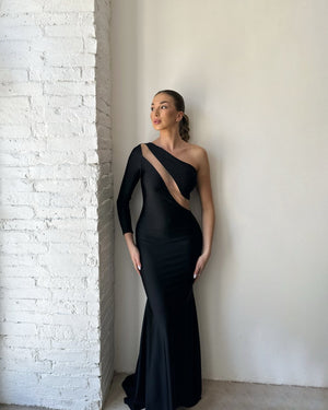 one shoulder black evening gown against brick wall