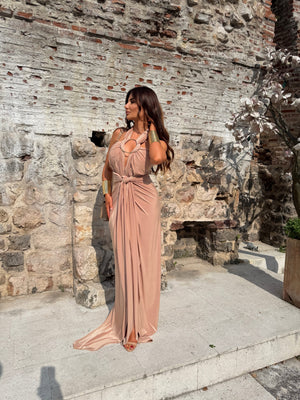 woman in elegant blush dress standing against stone wall