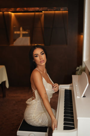 woman in sparkling white dress sitting at piano