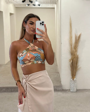 woman wearing a colorful halter top and beige wrap skirt