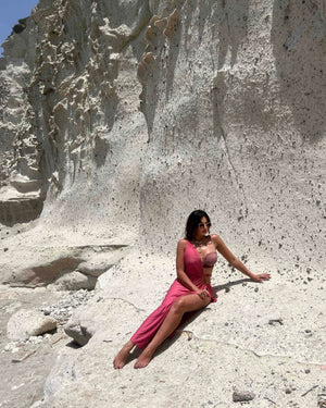 woman in pink dress sitting on rocky landscape
