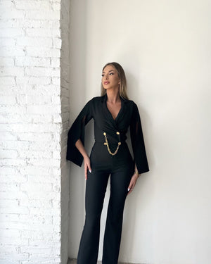 black jumpsuit with gold buttons and chain detail
