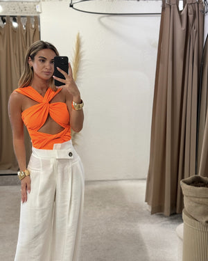 woman wearing orange top and white pants in dressing room