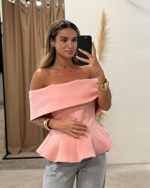 woman wearing pink off shoulder top and jeans in fitting room