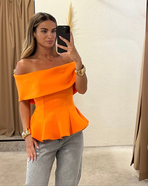 woman wearing orange off shoulder top and jeans
