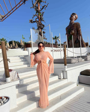 woman wearing peach dress on white steps under blue sky