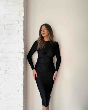 black long sleeve midi dress against white brick wall