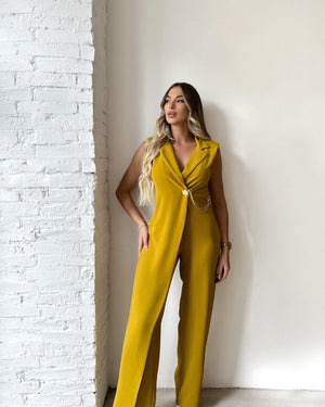 woman in yellow jumpsuit standing against white wall