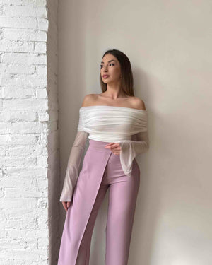 woman in off shoulder top and pink pants standing indoors
