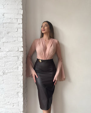 woman in pink and black dress with bell sleeves standing against white wall