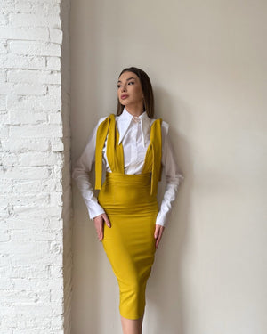 yellow dress over white shirt against textured wall
