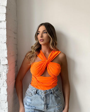 woman wearing bright orange top and ripped denim shorts