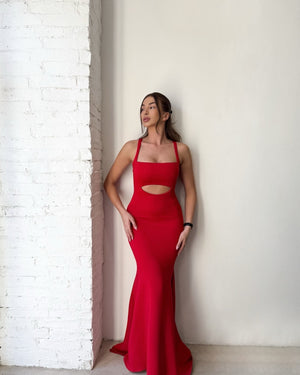 woman in red cutout dress against brick wall