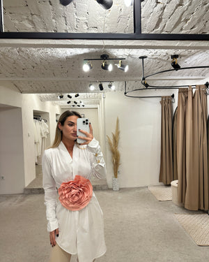 woman in white dress with pink flower detail indoors